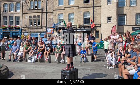 Edinburgh city centre, Scotland, UK. 13th August 2022. 9th Day for the Edinburgh Festival Fringe and the Film and Book festival also began this weekend so very busy with visitors enjoying the temperature of 22 degrees centigrade befor the haar arrived from the east coast mid afternoon. Pictured: Pete Anderson street performer entertaining an audience in The Grassmarket.  Credit: ArchWhite/alamy live news. Stock Photo