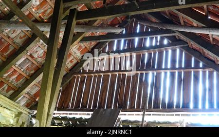 The sun's rays break through the wooden wall of this attic. It's a old forgotten building, a lost place Stock Photo