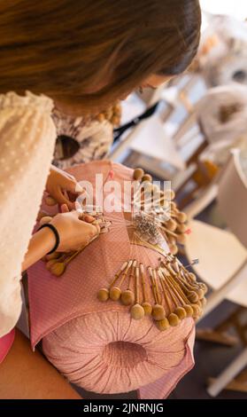 bobbin lace handcrafting. Women braiding threads to make a pattern. Stock Photo