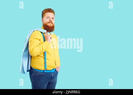 Redhead Caucasian man with beard and mustache wearing yellow shirt and jeans stands on studio Stock Photo