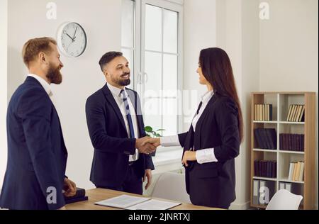 Business people end meeting by shaking hands with each other as sign of successful partnership. Stock Photo