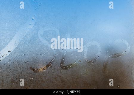 the word stop written on night wet window glass close-up with blurred background Stock Photo