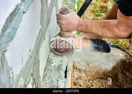 Cutting masonry with angle grinder and concrete cut saw. Electric hand power tool for dry cutting creates cloud of dust hazardous to health. Stock Photo