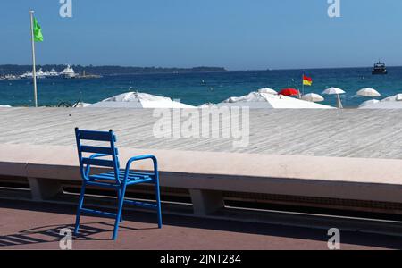 One of the iconic Blue Chairs which famously line the Promenade de la Croisette, Cannes. The blue represents the Mediterranean and the azure sky. Stock Photo