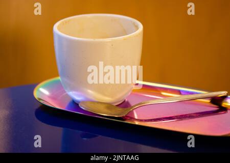 White ceramic cup without handle for cappuccino latte tea stands on stylish pink tray on blue table. Breakfast in a cafe, restaurant. A beautifully ch Stock Photo