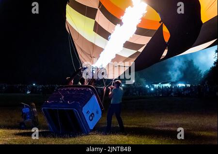 Heldburg, Germany. 13th Aug, 2022. Hot air balloonists heat the air in the hot air balloon with a gas burner. The 25th Thuringian Montgolfiade, the German hot air ballooning championship, takes place in Heldburg. Of the 58 hot air balloons registered, 33 take part in the competition. Credit: Daniel Vogl/dpa/Alamy Live News Stock Photo