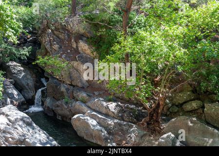 Image of a waterfall surrounded by green rocky landscape Stock Photo