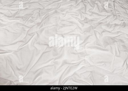 Close-up of the texture of a crumpled white sheet with tinted folded lines Stock Photo