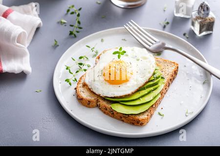 Avocado toast on a toasted multigrain bread with a fried egg Stock Photo