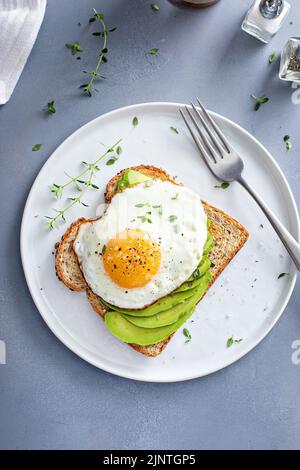 Avocado toast on a toasted multigrain bread with a fried egg Stock Photo