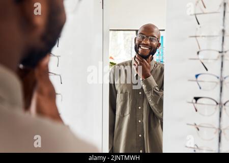 Customer trying on glasses at an optometrist, smiling and looking confident with choice at optical store . Carefree man buying trendy spectacles to Stock Photo