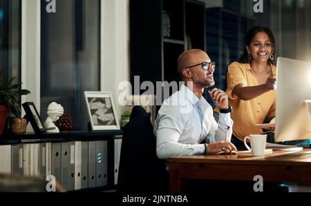 Diverse business people designing on computer, talking in meeting and planning marketing strategy while working late in an office at work together Stock Photo