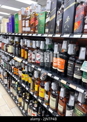 BALTIMORE, MD - AUGUST 11, 2022: Shelves are stocked full of pricey whiskey and other liquor bottles all protected with locked on security devices to Stock Photo