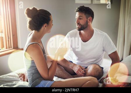 After breakfast we discuss what to do for the day. a happy young couple enjoying breakfast in bed together at home. Stock Photo