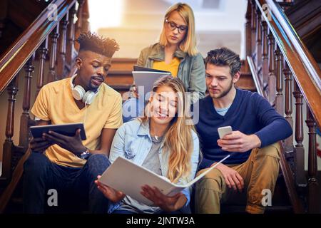 Working on a task together. a group of diverse university students working together on the staircase on campus. Stock Photo