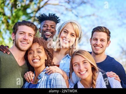 Campus break, time to chill. Portrait of a group of diverse students hanging out together outside on campus. Stock Photo