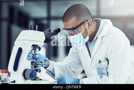 Serious young male scientist working on scientific cure for covid in a lab. Professional man in science at work during pandemic on a medical mission Stock Photo