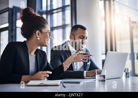 Doubling up on their efforts and expertise. two businesspeople working together on a laptop in an office. Stock Photo