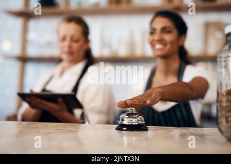 Waitress hands ringing service bell for a ready order in cafe, restaurant and coffee shop. Waitresses, servers and baristas serving, assisting or Stock Photo