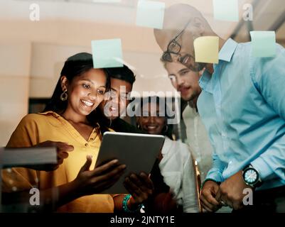 Group of creative, excited and smiling design team, working, researching and browsing on tablet for innovation ideas in modern office. Office workers Stock Photo