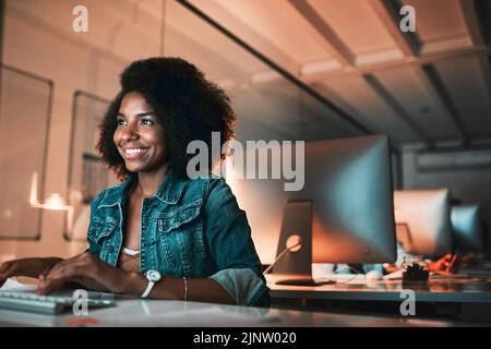 Feeling positive about her progress. an attractive young female designer looking confident while working on her computer in the office. Stock Photo
