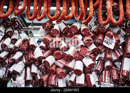 We keep our meat lovers happy too. different types of cured meats stacked on top of each other at a stall to be sold at a market during the day. Stock Photo