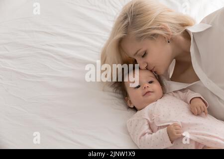 Young loving mother kisses on forehead her lovely newborn Stock Photo