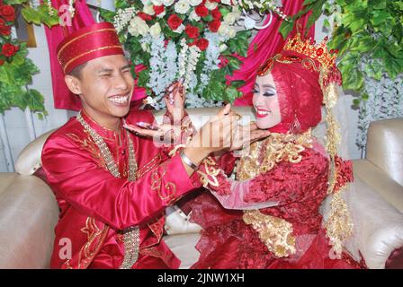 Tegal, INDONESIA - August 17 2020: Two Muslim bridal couples share a meal each other Stock Photo