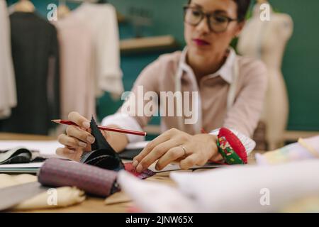 Female dressmaker choosing fabric from swatch. Focus on female hand with fabric sample. Stock Photo