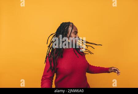 Cheerful woman smiling and whipping her dreadlocks while standing