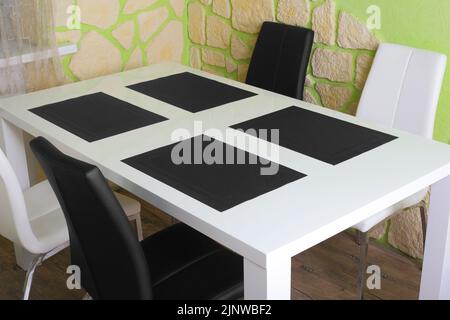 Dining table and chairs in the interior against a green wall and stone background Stock Photo
