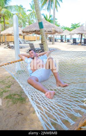 men relaxing in a hammock during a tropical heat wave global warming concept, hot temperature during a summer heat wave Stock Photo