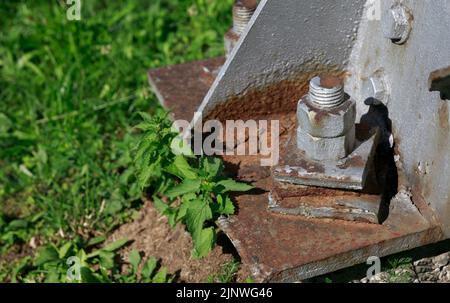 On the rusty metal base of the column, a rusty bolt is firmly attached Stock Photo