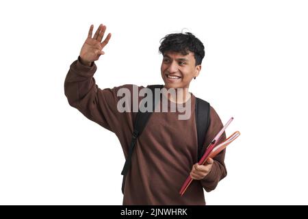 Young peruvian student waves and smiling, holds folders and backpack, isolated. Stock Photo