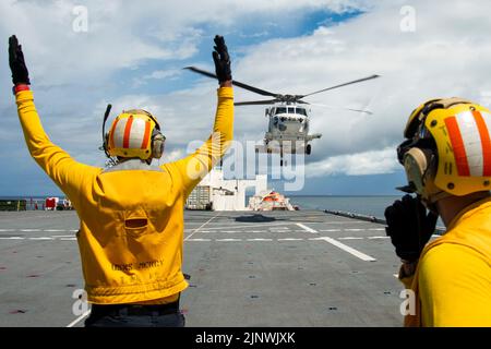 July 19, 2022 - Koror, Palau - Aviation Boatswains Mate 3rd Class Nelson Benetmorales signals a SH-60K helicopter attached to Japan Maritime Self-Defense Force ship JS Kirisame (DD 104) aboard Military Sealift Command hospital ship USNS Mercy (T-AH 19) as part of a multilateral search and rescue exercise coordinated with the U.S. Navy, Republic of Palau, U.S. Coast Guard, Japan Maritime Self-Defense Force and Royal Navy in support of Pacific Partnership 2022. Now in its 17th year, Pacific Partnership is the largest annual multinational humanitarian assistance and disaster relief preparedness m Stock Photo