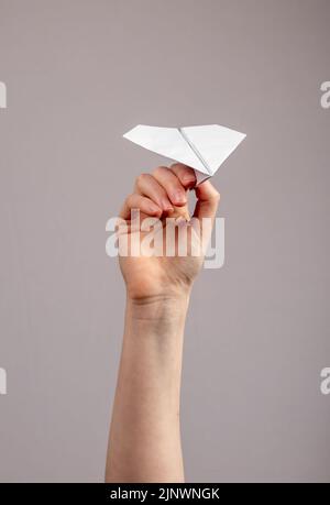Paper air plane origami toy in hands closeup. Concepts of aircraft travel trip or sending messages news. Stock Photo
