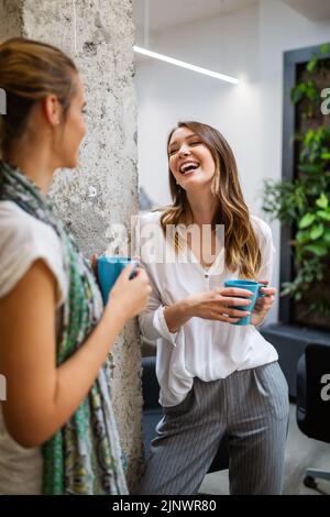 Office coffee break with two business female colleagues having fun chatting over cups of coffee Stock Photo