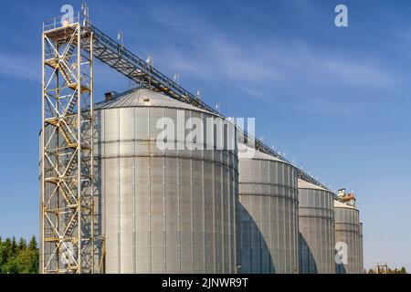 Large metal elevator tanks against a bright blue sky. Silo or granary at sunny day Stock Photo