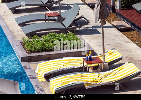 Empty sun loungers at swimming pool at beachfront hotel, Pattaya, Chon Buri, Thailand Stock Photo
