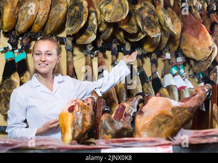 Glad woman selling prosciutto meat Stock Photo