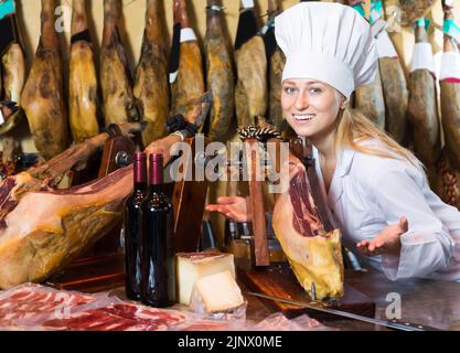 Portrait of glad woman selling prosciutto meat Stock Photo