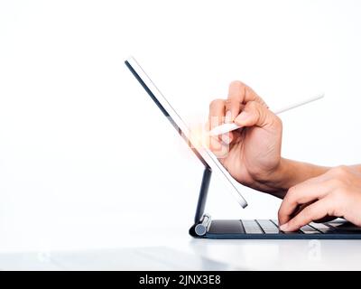 Electric pencil in business person's hand, writing or drawing on digital tablet screen while typing on keyboard computer isolated on white background Stock Photo