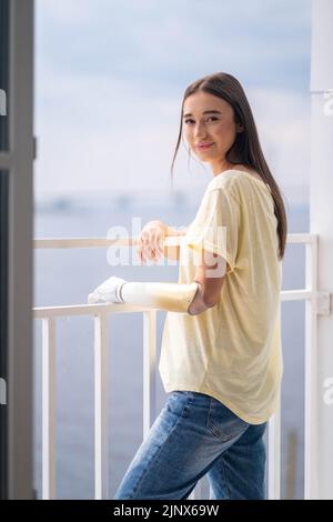 Portrait happy woman with prosthetic arm relaxing at home, girl with disability artificial prosthetic limb. Stock Photo