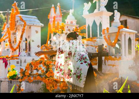 A Mixtec indigenous woman decorates a tomb at a cemetery during the Day of Dead celebrations in Xalpatlahuac, Guerrero, Mexico. Stock Photo