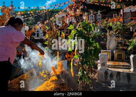 A Mixtec indigenous woman decorates a gravesite at a cemetery during the Day of the Dead celebrations in Xalpatláhuac, Guerrero, Mexico. Stock Photo