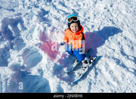 View from above of smiling little boy with ski and winter outfit Stock Photo