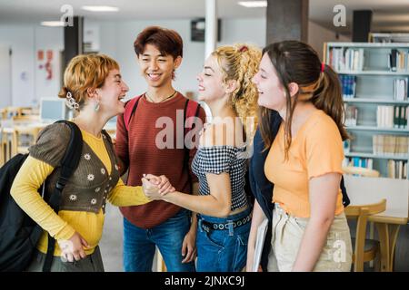 Small group of students greeting each other in the university library Stock Photo