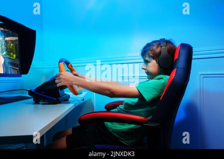 Side portrait with console steering wheel of a gamer teen boy Stock Photo