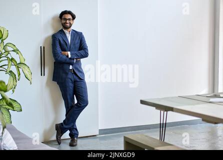Smiling young indian business man wears suit stands in office, portrait. Stock Photo