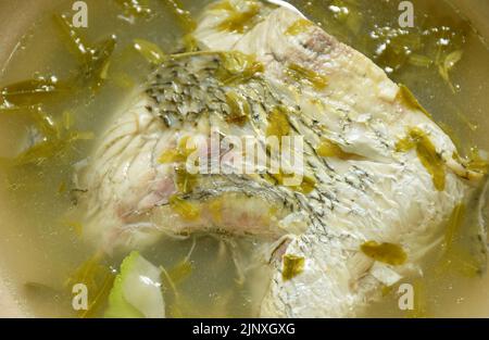 spicy bass fish head and tamarind leaf in Tom Yum soup on bowl Stock Photo